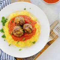 Overhead view of spaghetti squash with meatballs and marinara on plate.
