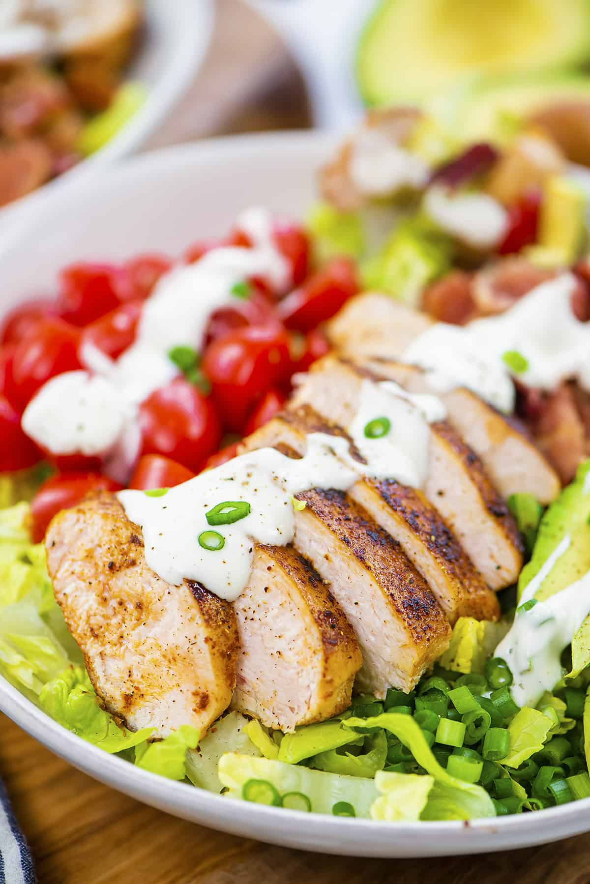Sliced chicken on salad topped with ranch dressing.