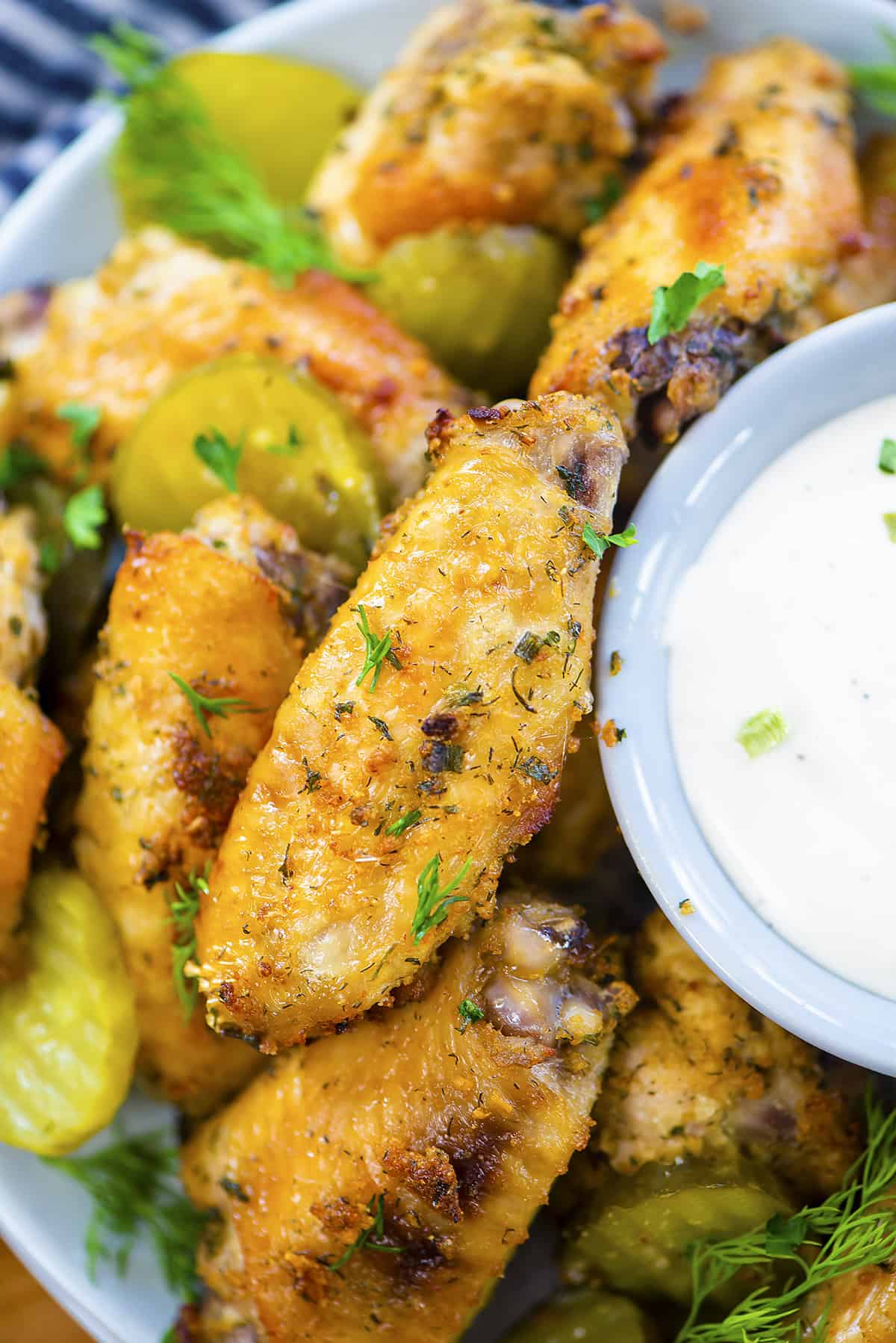 Baked ranch wings in bowl with pickles and ranch dressing.