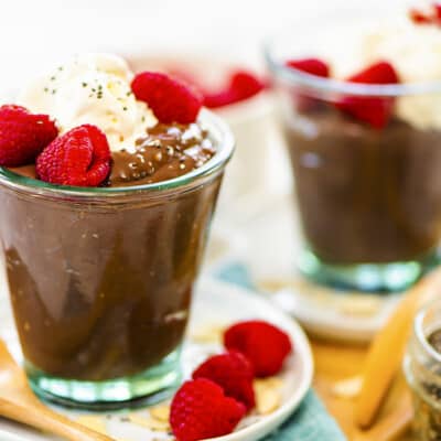 Keto chia pudding in jars topped with whipped cream and raspberries.