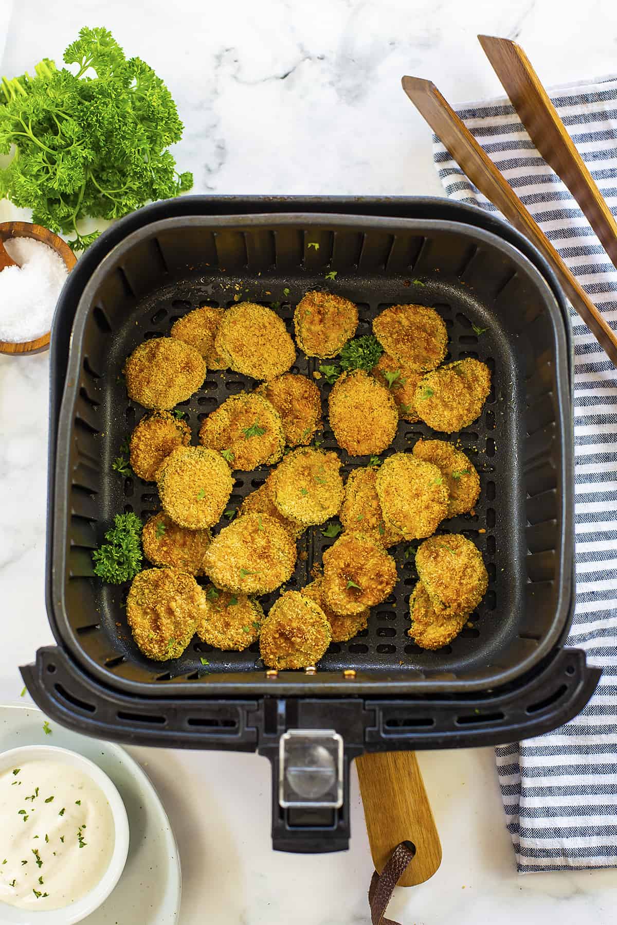 Keto fried pickles in air fryer basket.