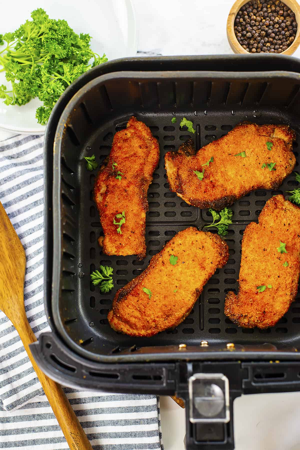 Pork chops in air fryer basket.