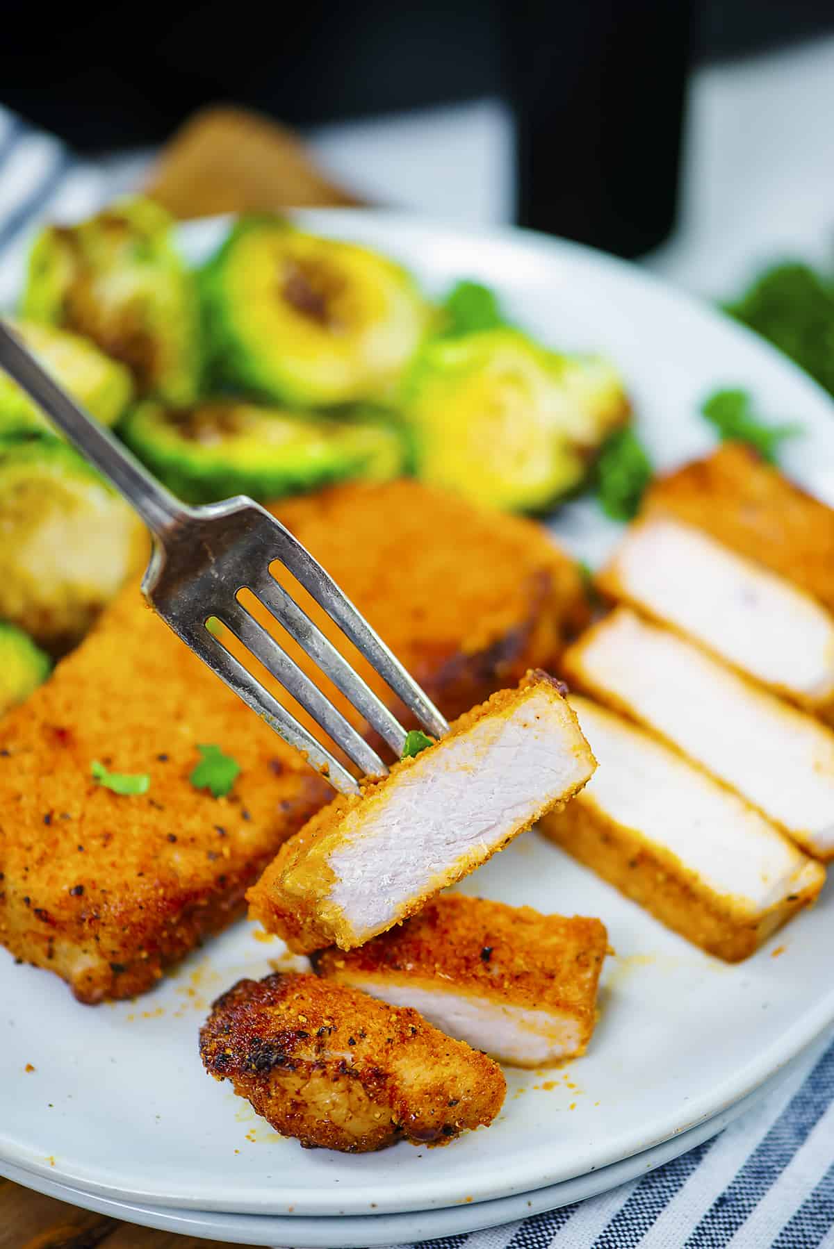 Sliced pork chops on plate with Brussels sprouts.