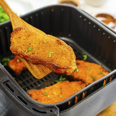 Pork chop being lifted out of air fryer.