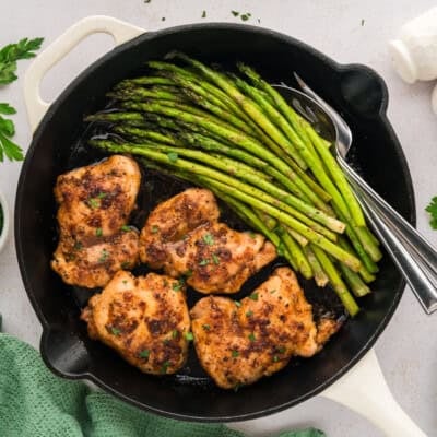 Garlic butter chicken and asparagus in skillet.