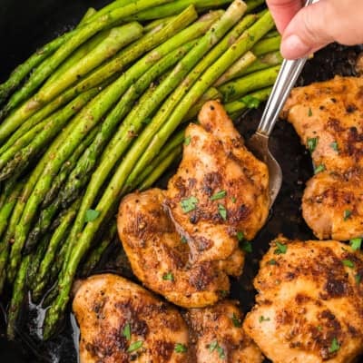 Chicken thighs in skillet with asparagus.