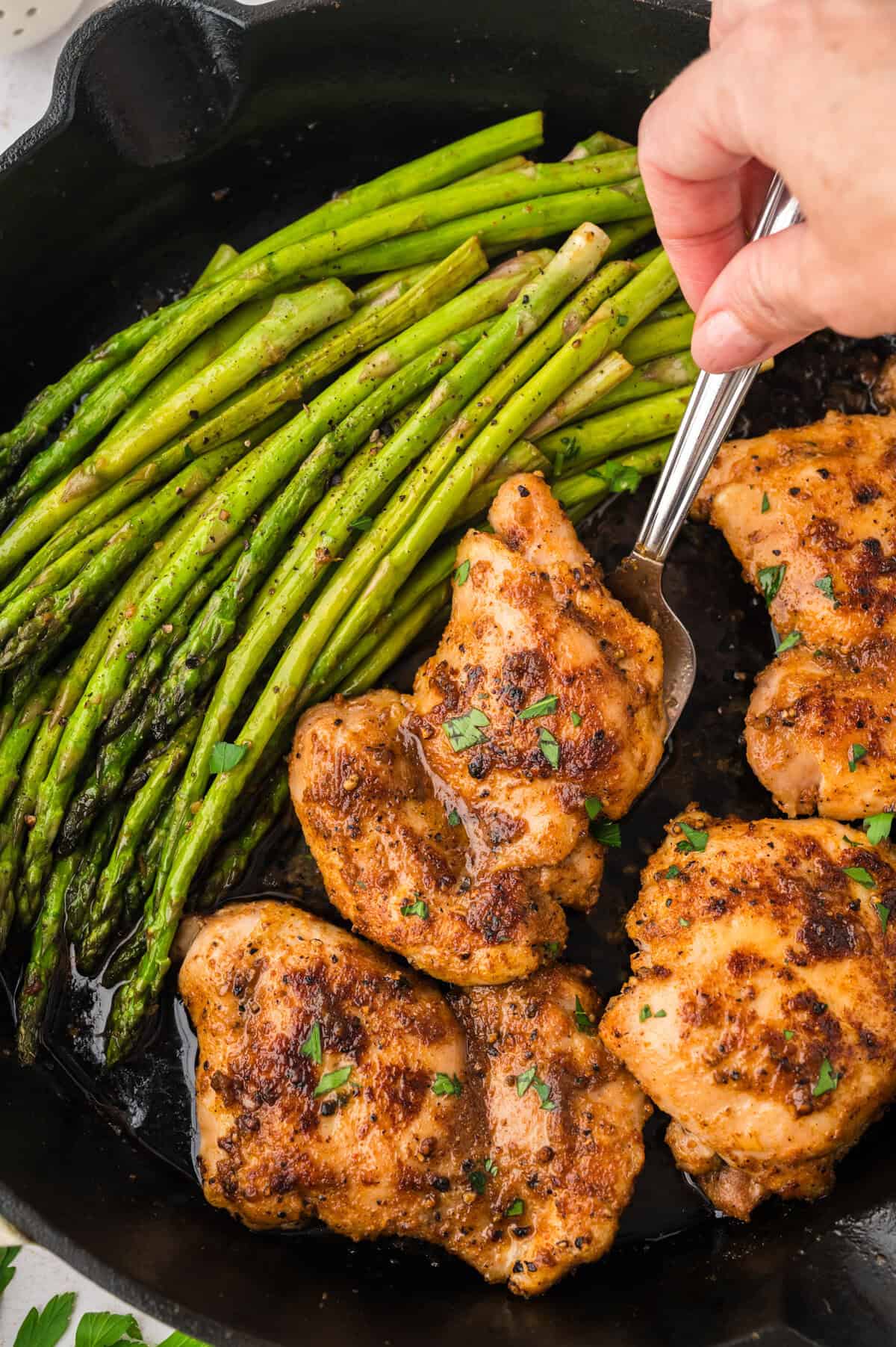 Chicken thighs in skillet with asparagus.