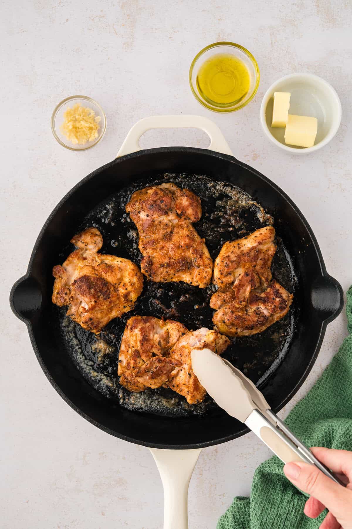 Chicken being cooked in a cast iron skillet.