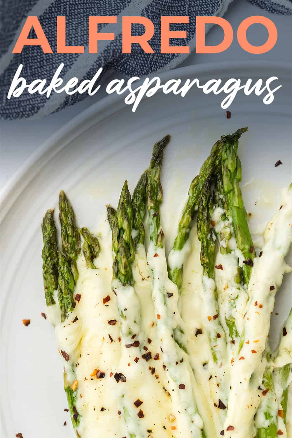 Asparagus on plate topped with alfredo sauce.