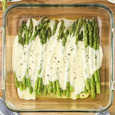 Alfredo topped asparagus in glass baking dish.
