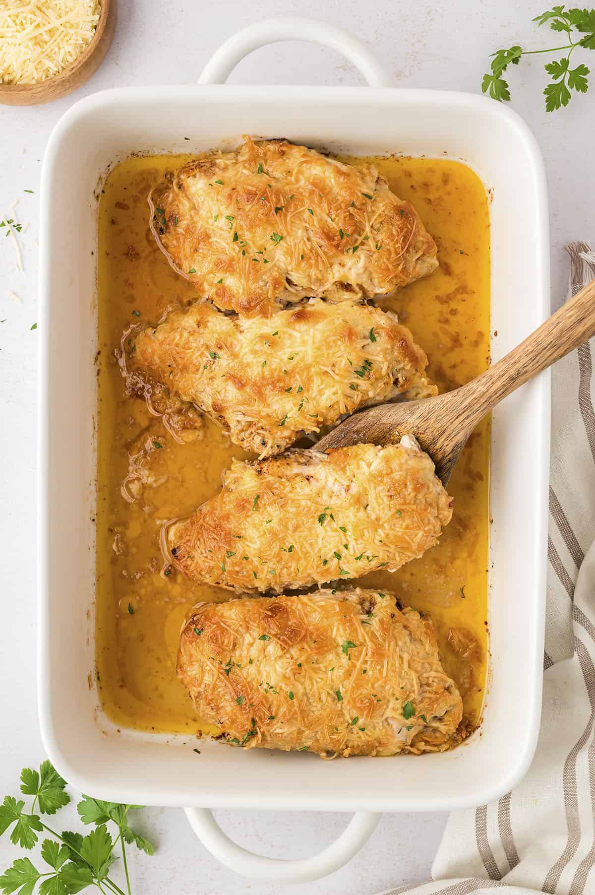 Baked parmesan crusted chicken with mayo in white baking dish.