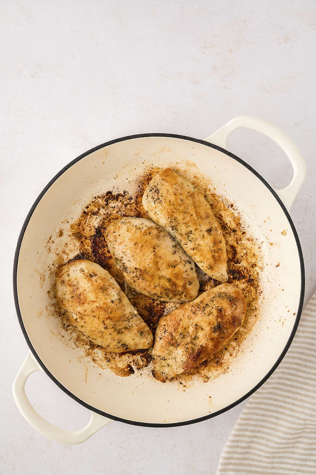 Seasoned chicken breasts cooked in white pot.