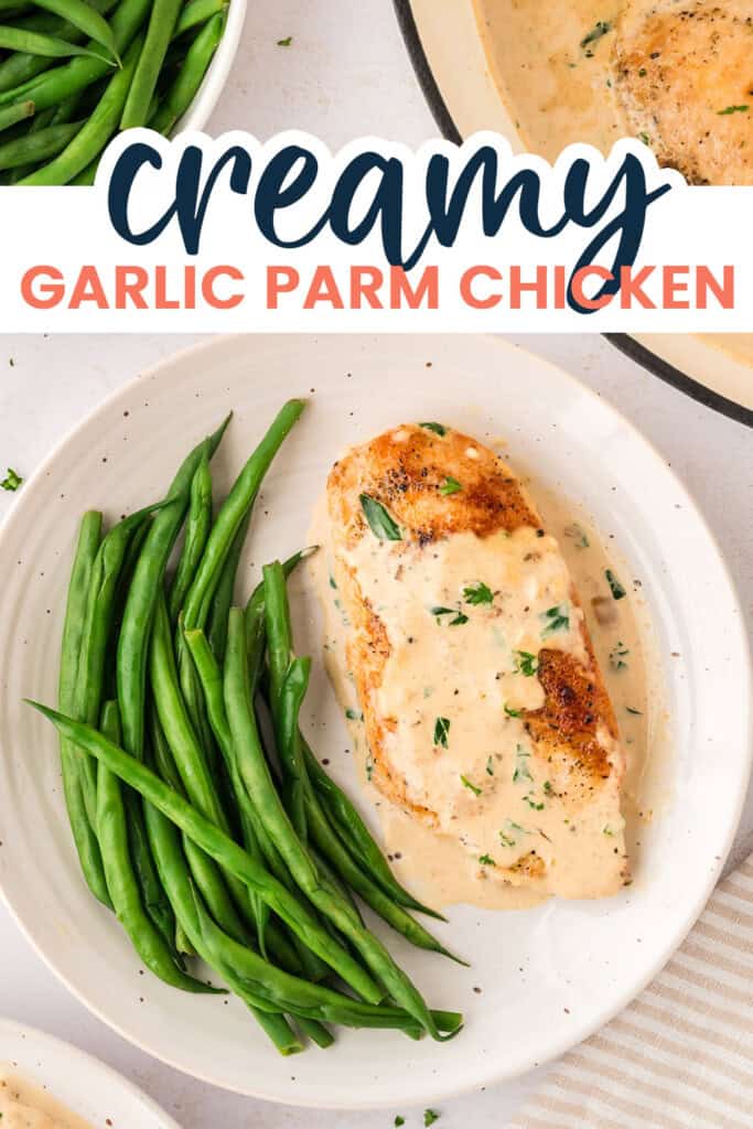 Creamy garlic parmesan chicken on white plate next to green beans.
