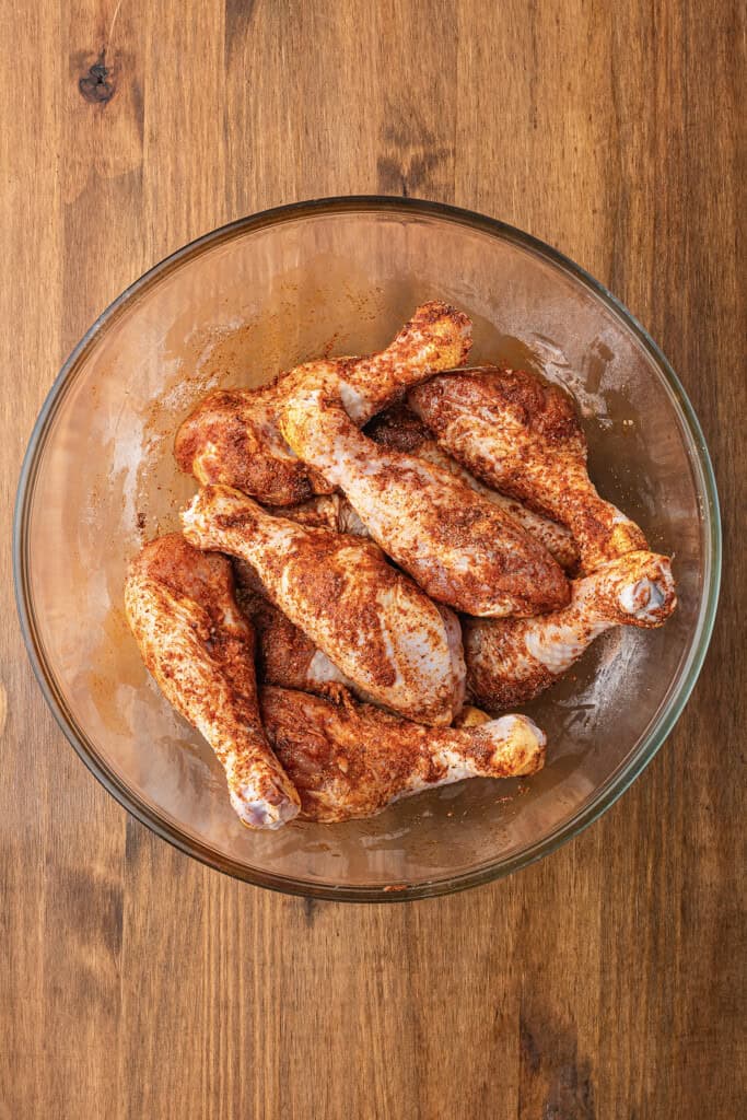 Seasoned drumsticks in glass bowl.