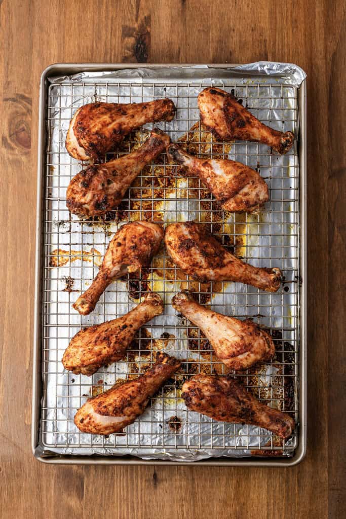 Baked chicken drumsticks on wire rack.