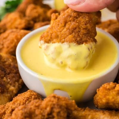 Chicken nugget being dipped in keto honey mustard.