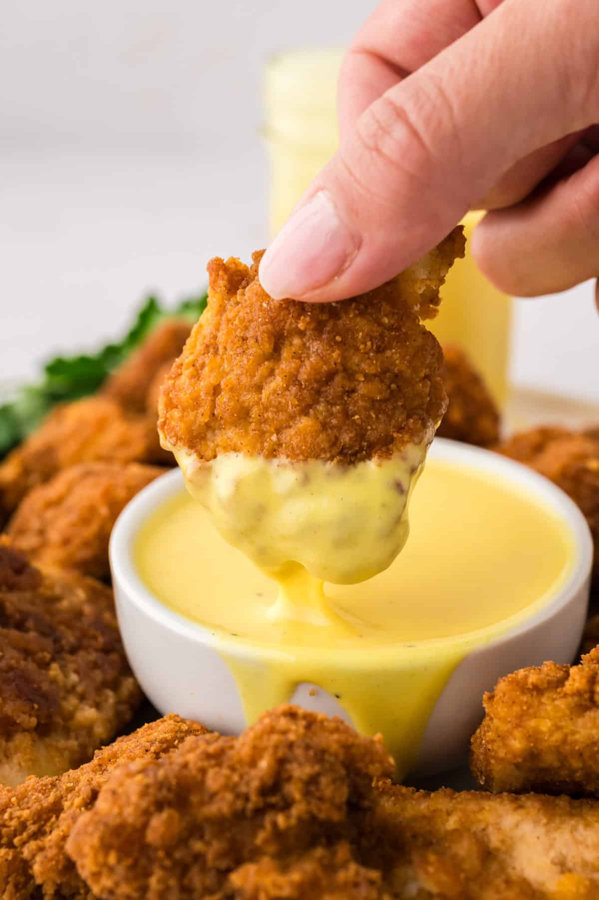 Keto chicken nugget being dipped in honey mustard dressing.