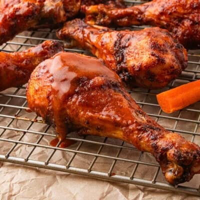 Baked buffalo chicken drumsticks on wire rack.