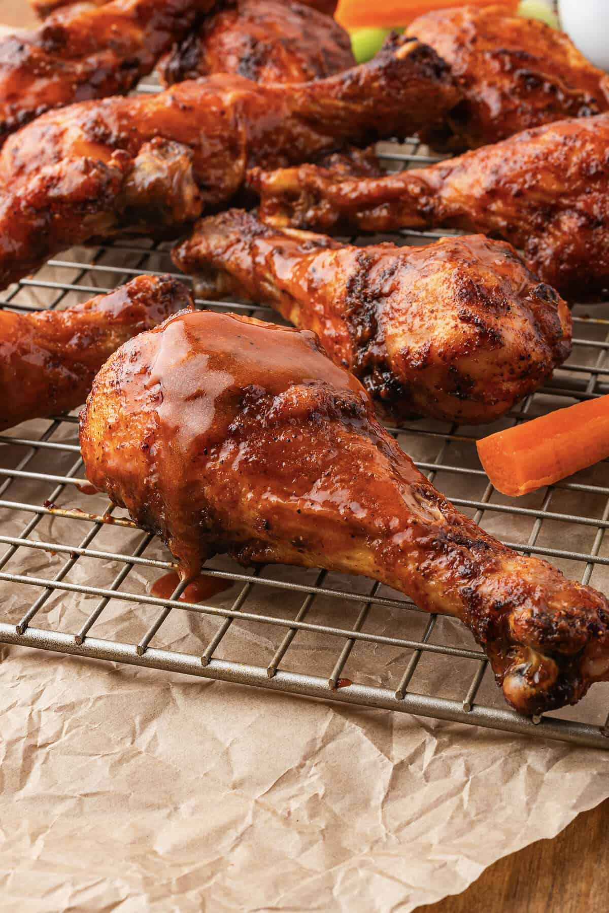 Baked buffalo chicken drumsticks on wire rack.