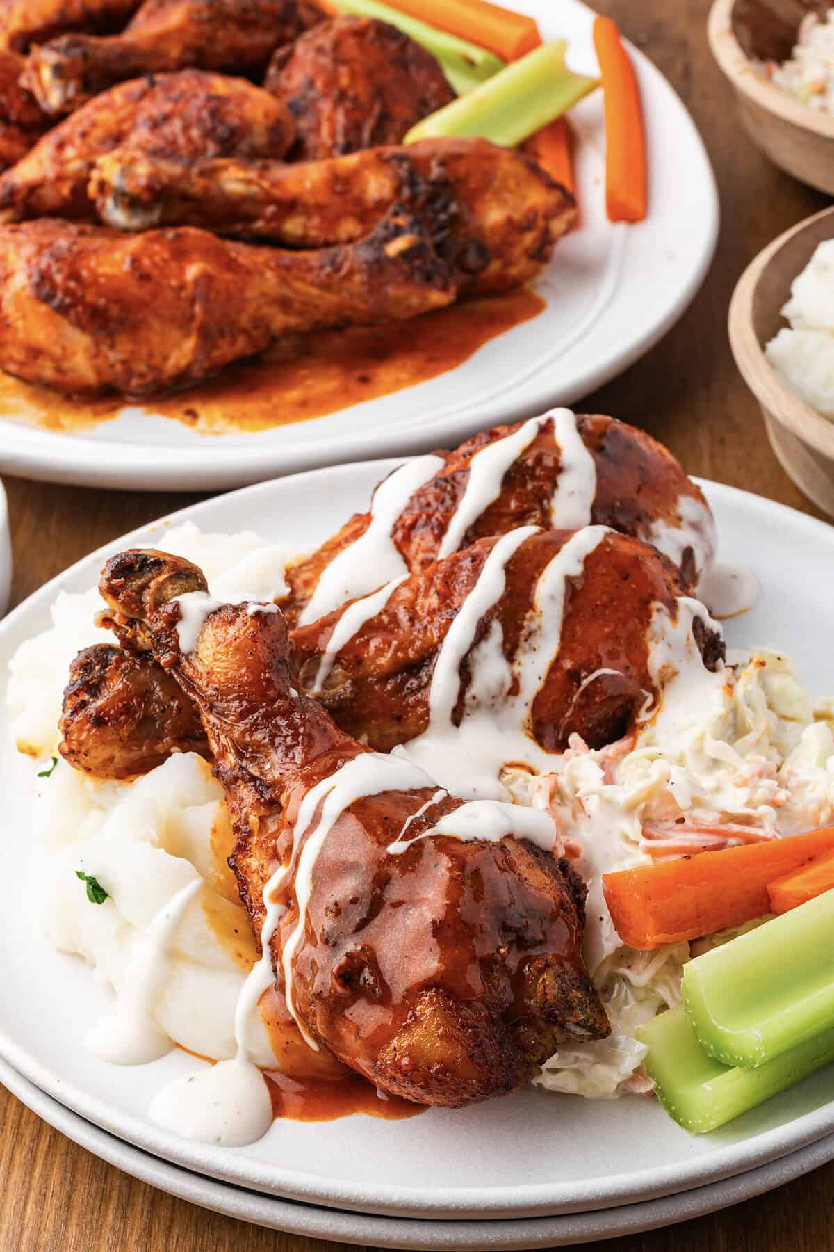 Baked buffalo chicken drumsticks on plate drizzled with ranch dressing.