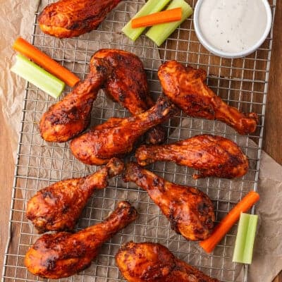 Easy buffalo chicken drumsticks on wire rack covered in sauce.