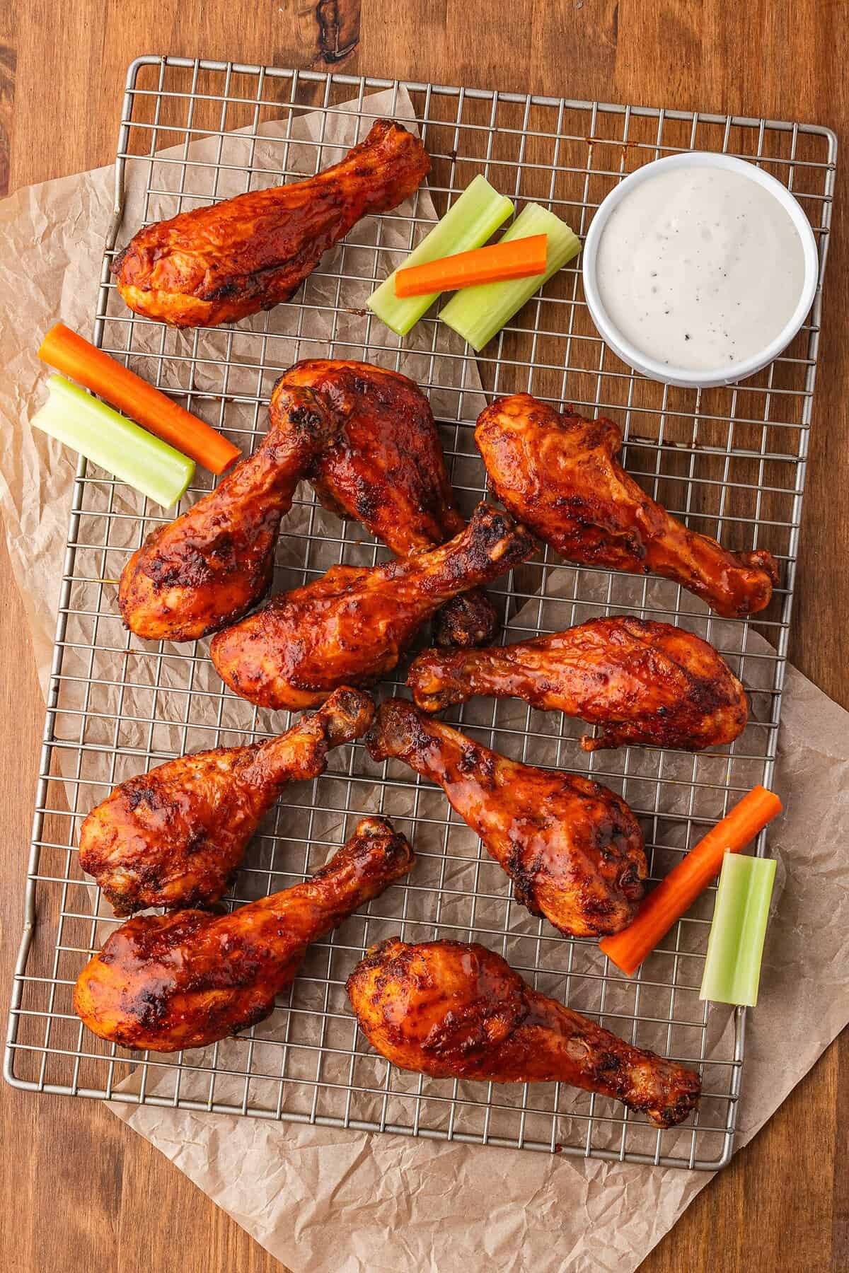 Easy buffalo chicken drumsticks on wire rack covered in sauce.