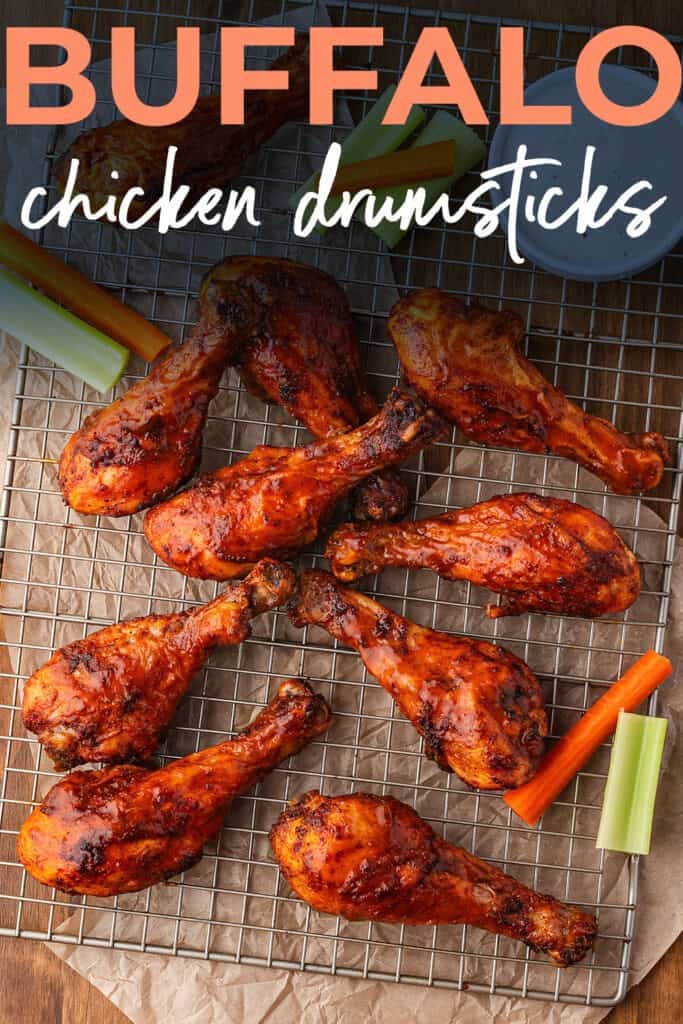 Buffalo chicken drumsticks on wire rack with celery and carrots.