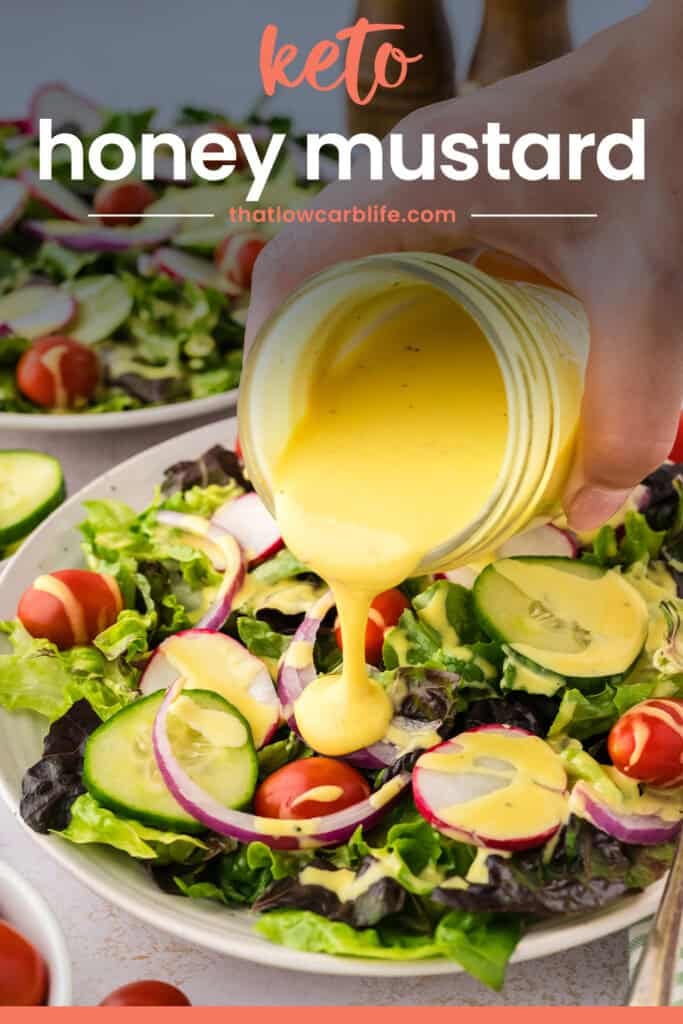 Honey mustard dressing being poured over a green salad.