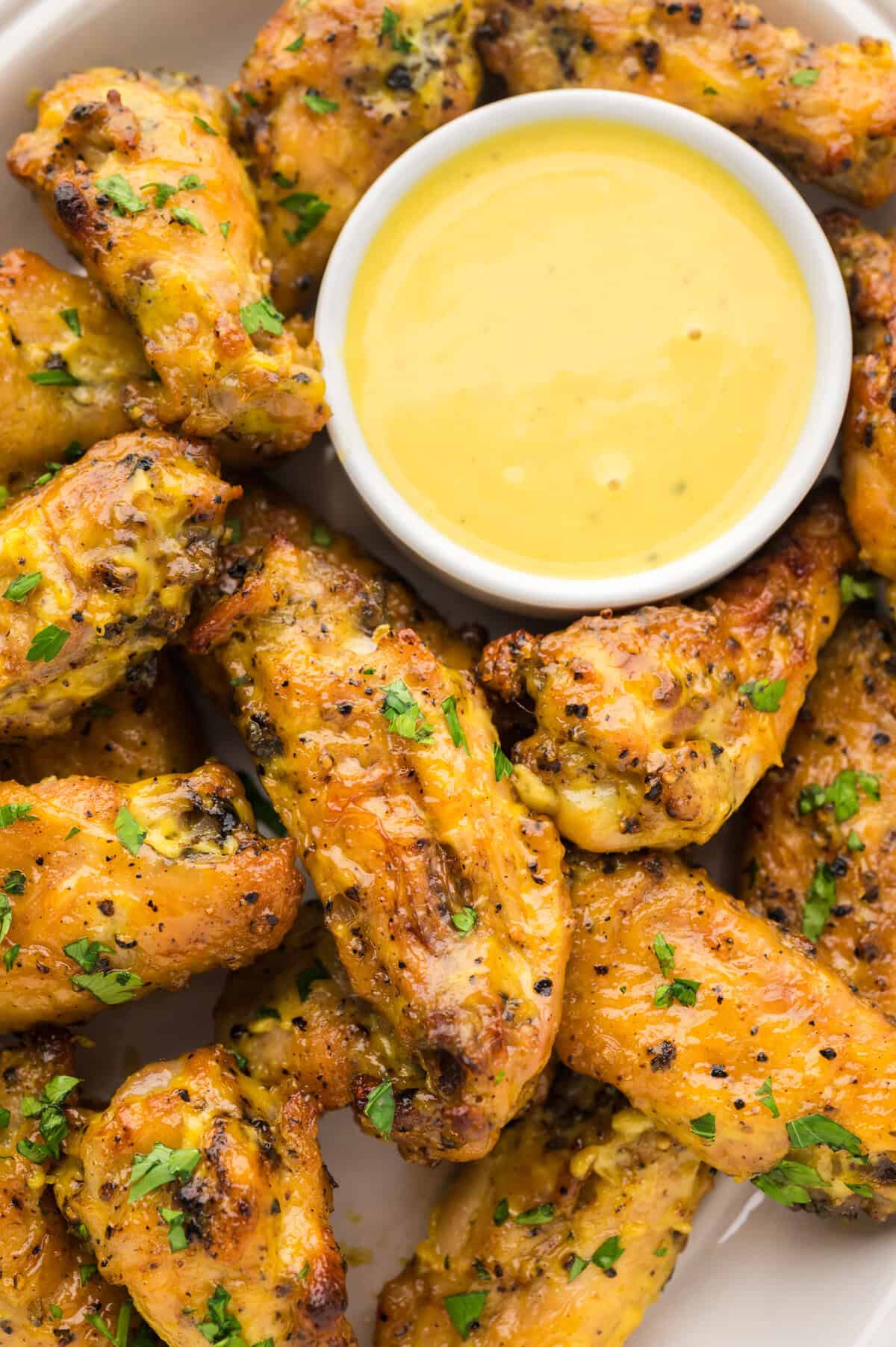 Keto honey mustard wings on platter with more honey mustard for dipping.