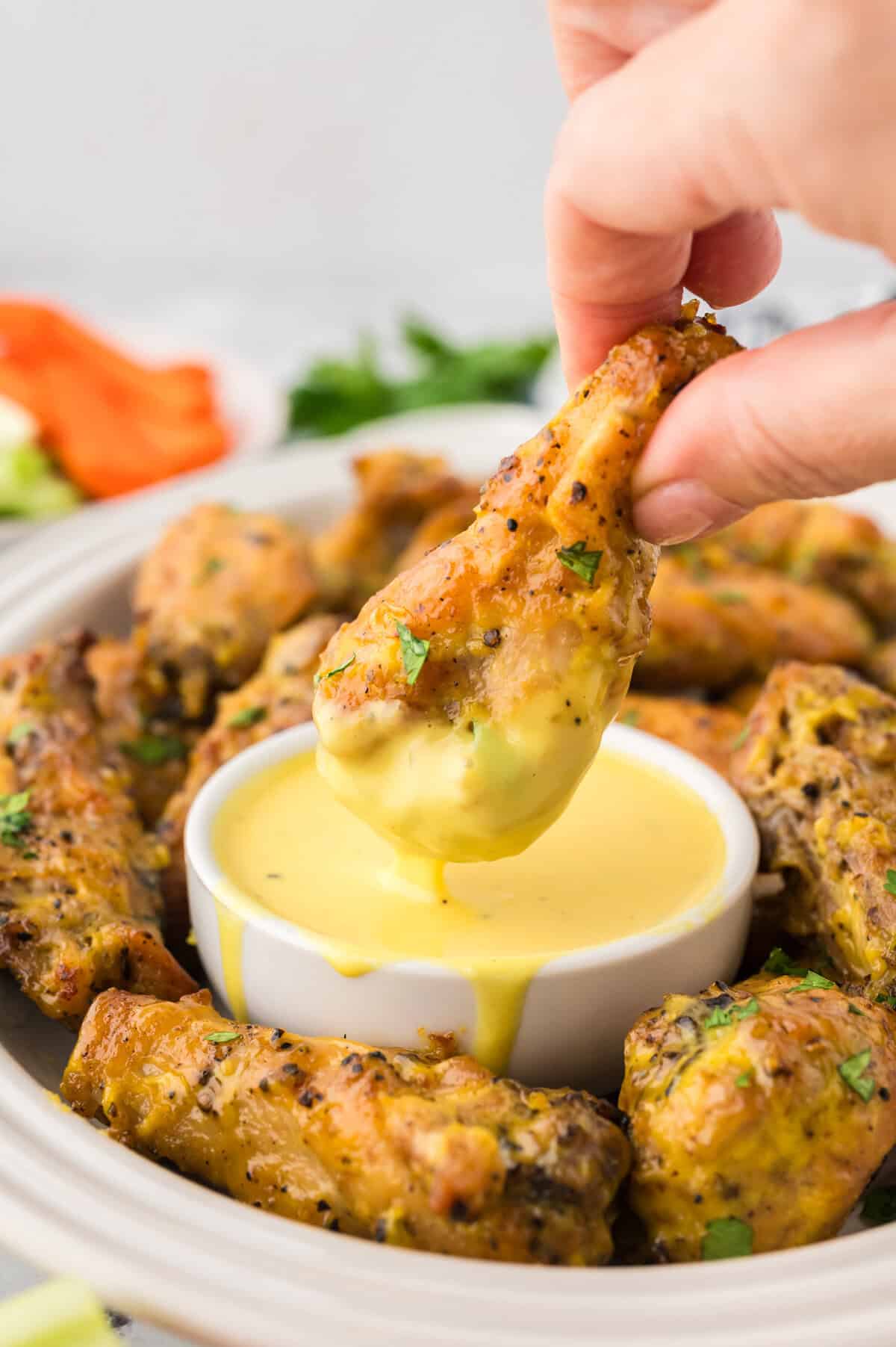 Keto honey mustard wing being dipped in honey mustard