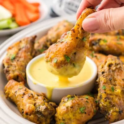 Chicken wing being dipped in keto honey mustard.