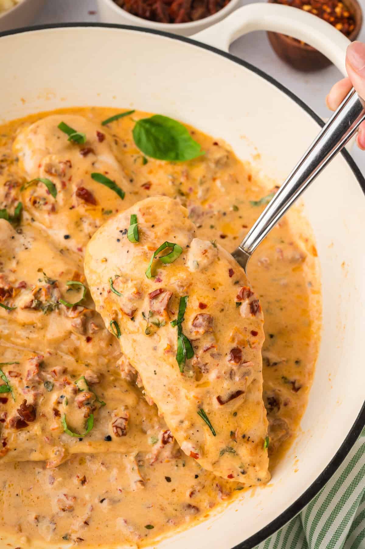 Keto marry me chicken on spoon being lifted over the pot.