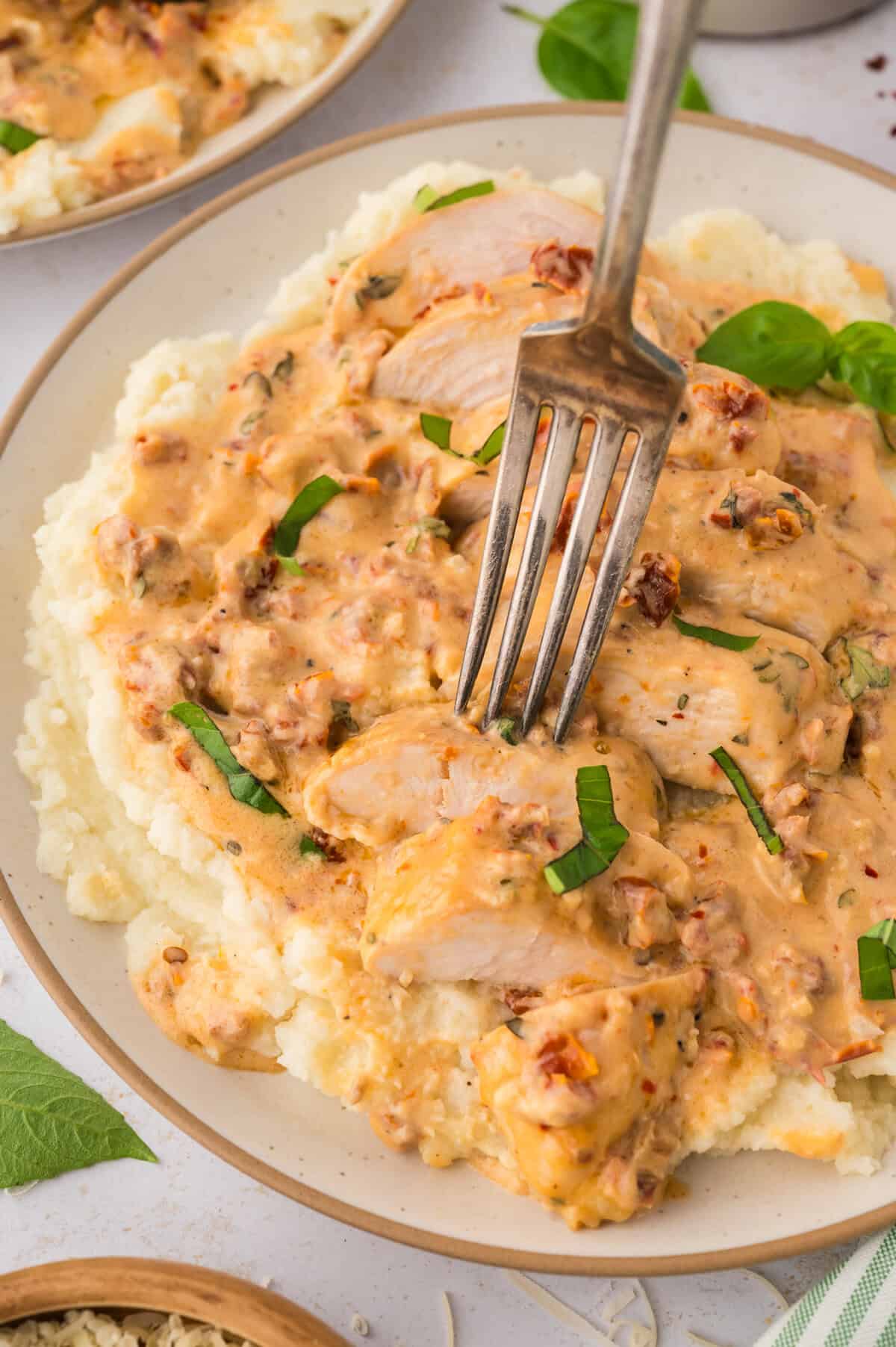 Fork full of keto marry me chicken on a bed of mashed cauliflower.