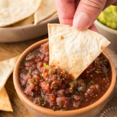 Keto tortilla chip being dipped in salsa.