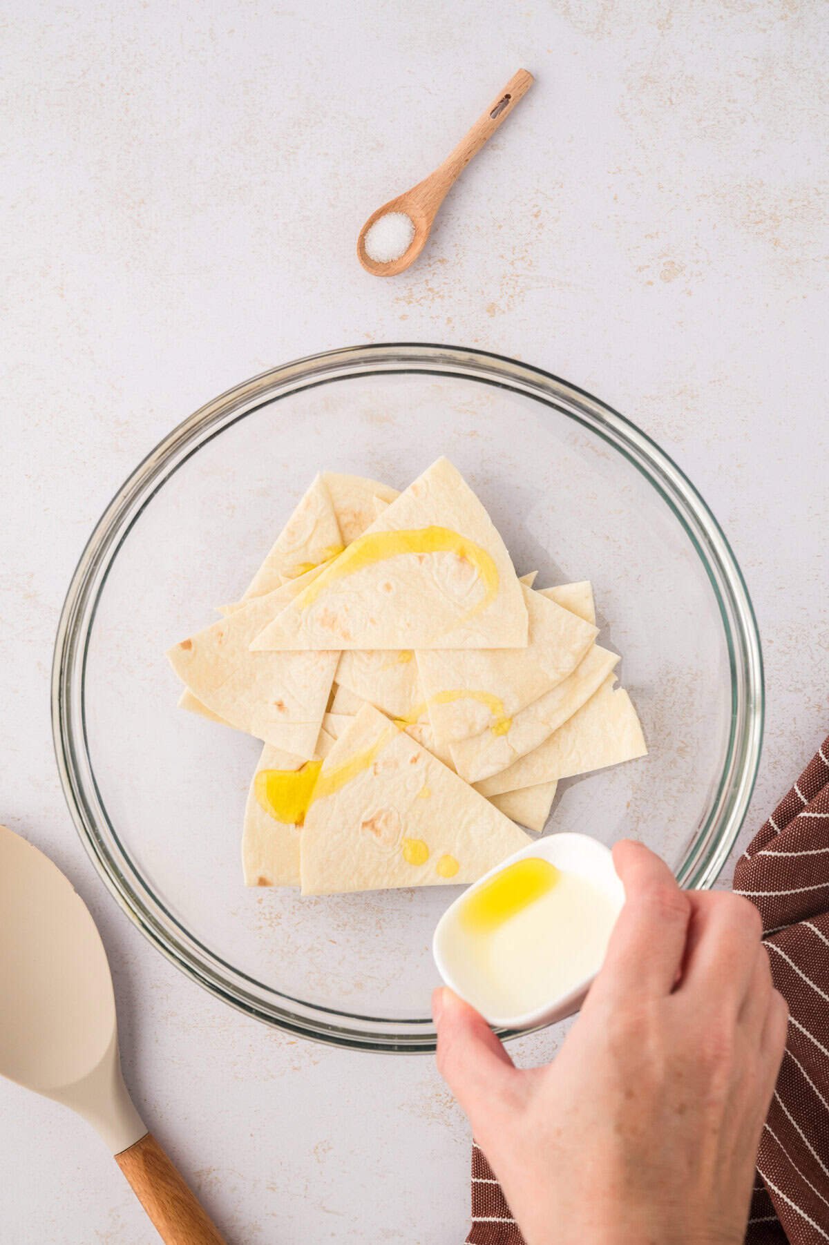 Tortillas being drizzled with oil.