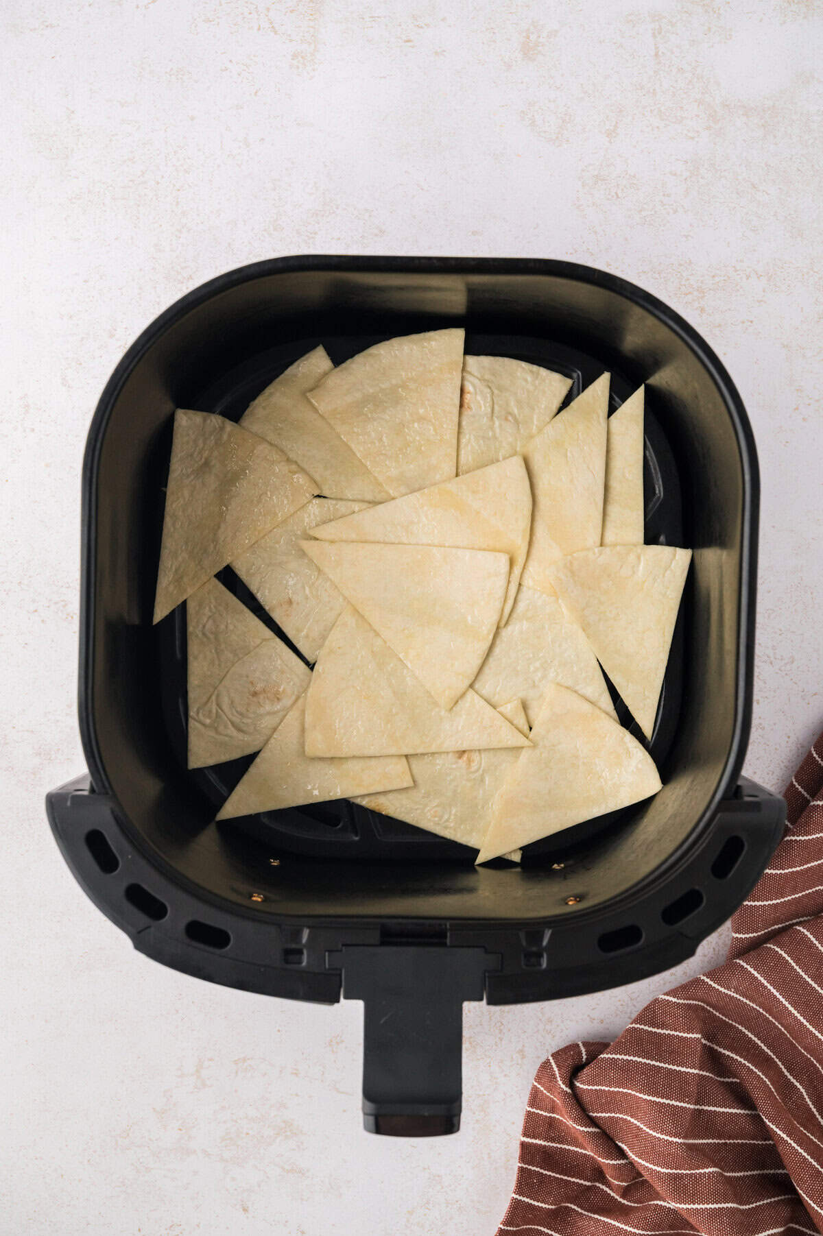 Tortilla chips in air fryer basket before cooking.