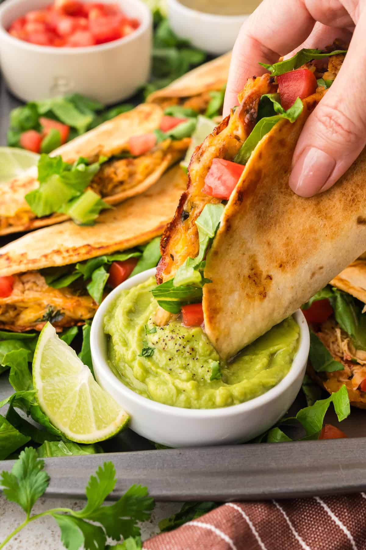 Crispy baked taco being dipped in guacamole.