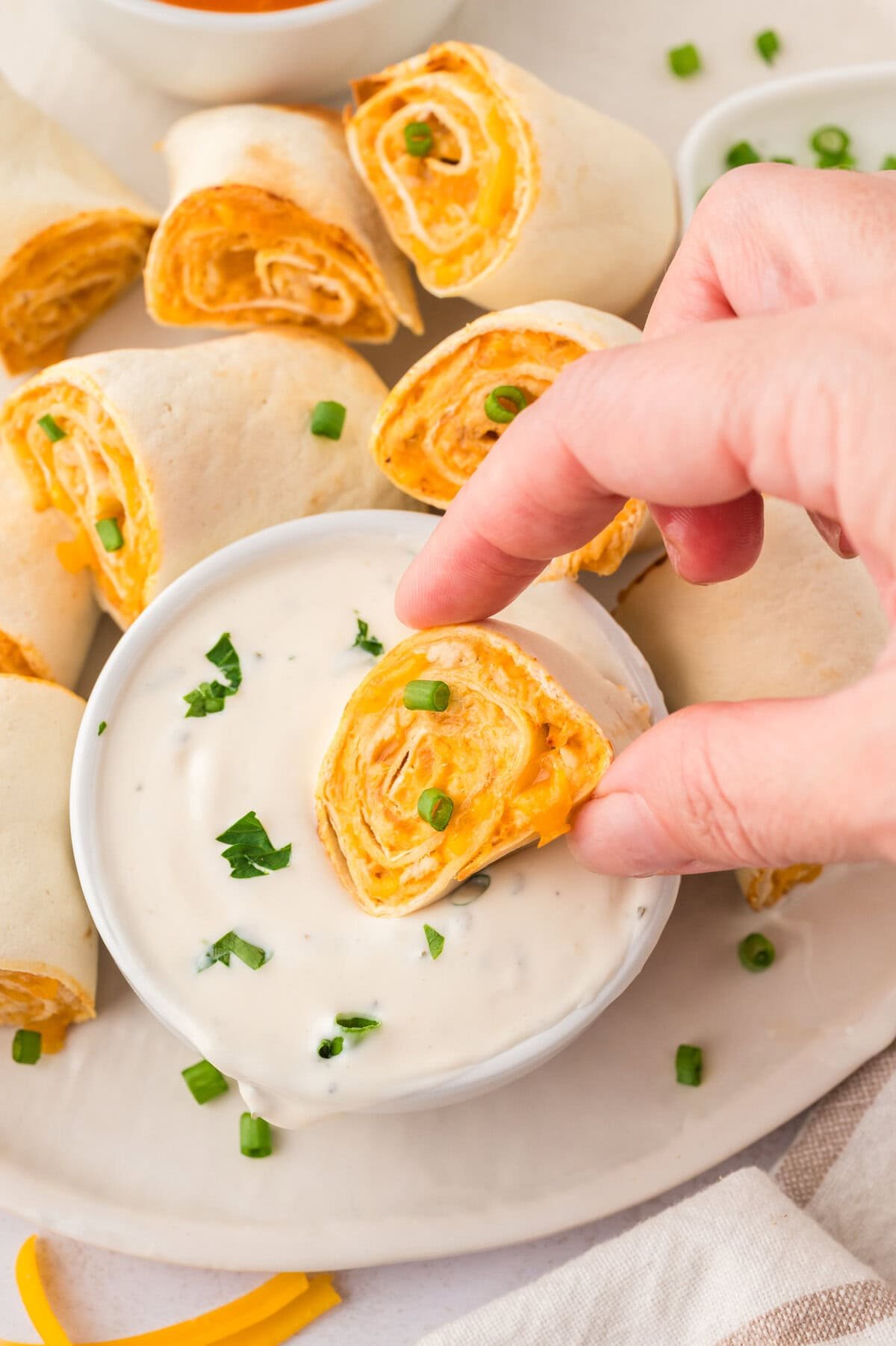 Hand dipping a buffalo chicken pinwheel into ranch.