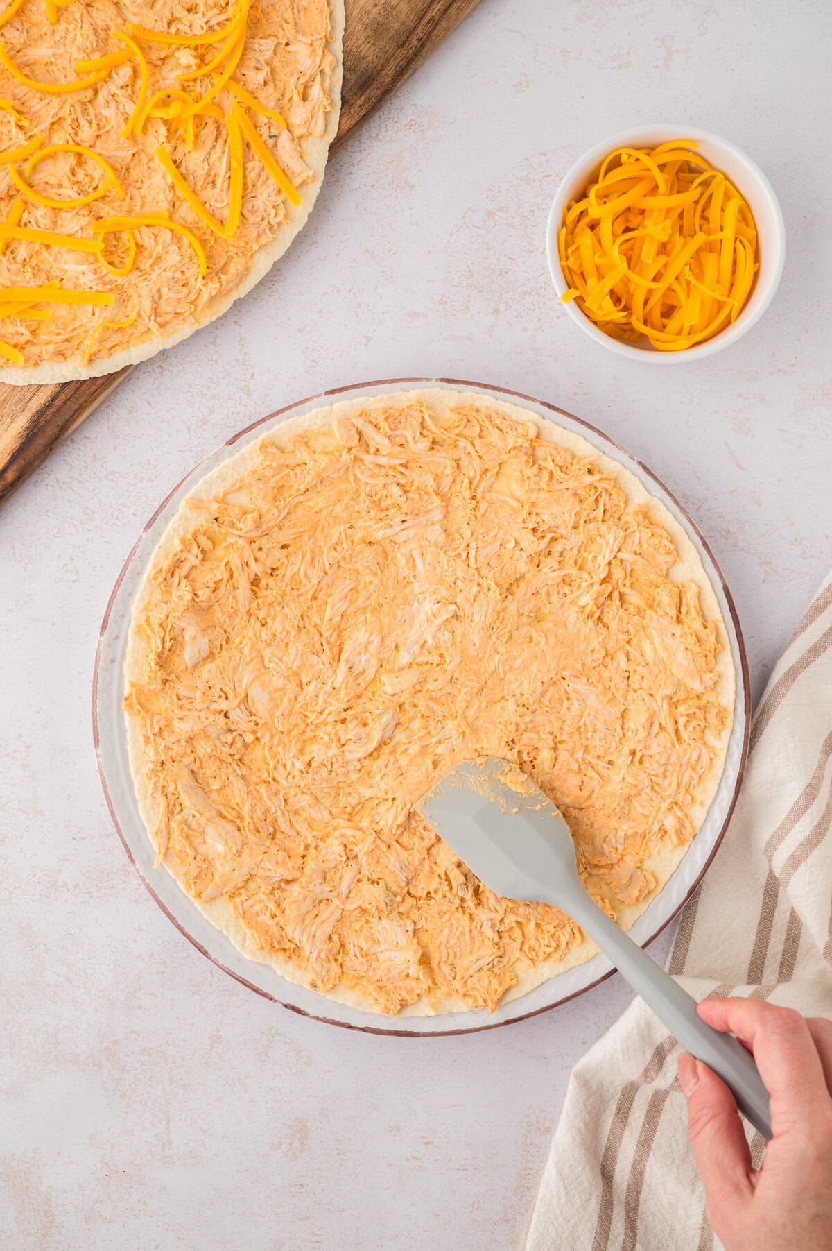 Buffalo chicken mixture being spread on tortilla.