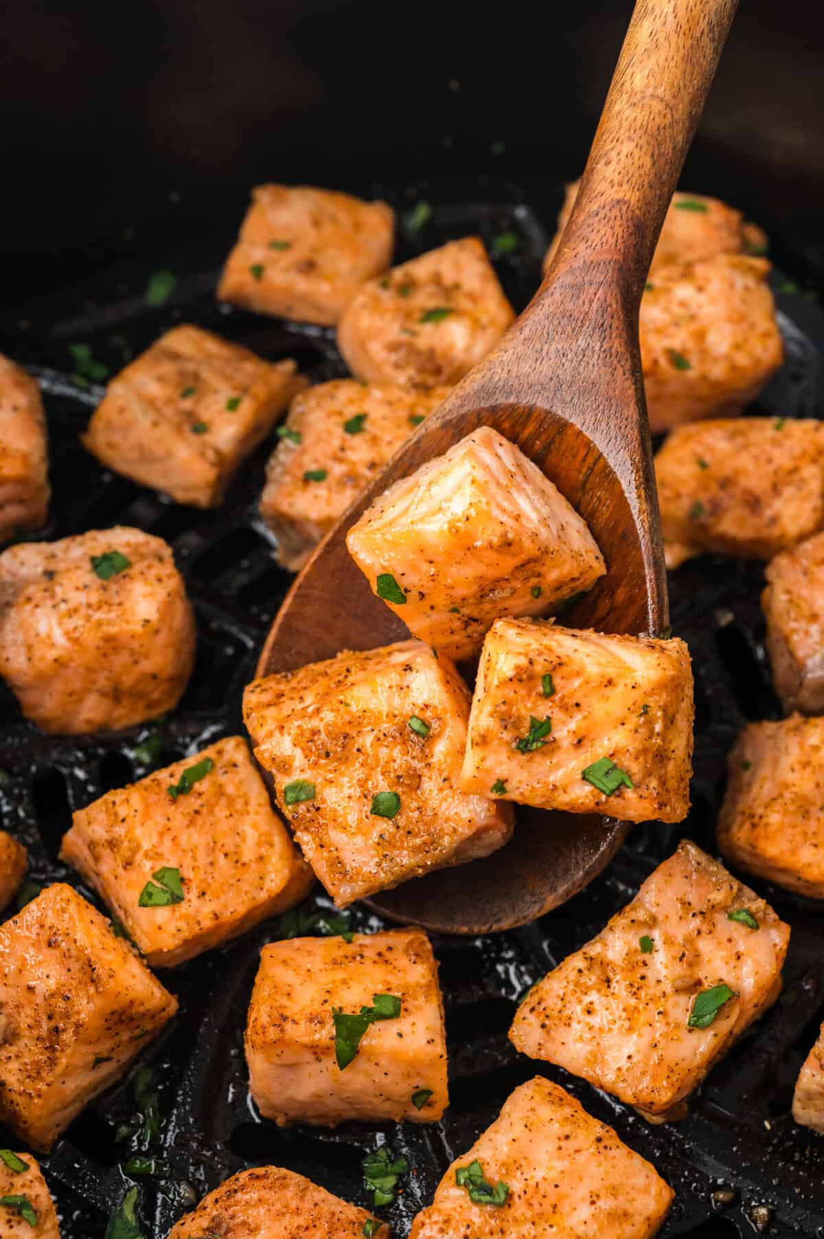 Cooked salmon bites in air fryer basket.