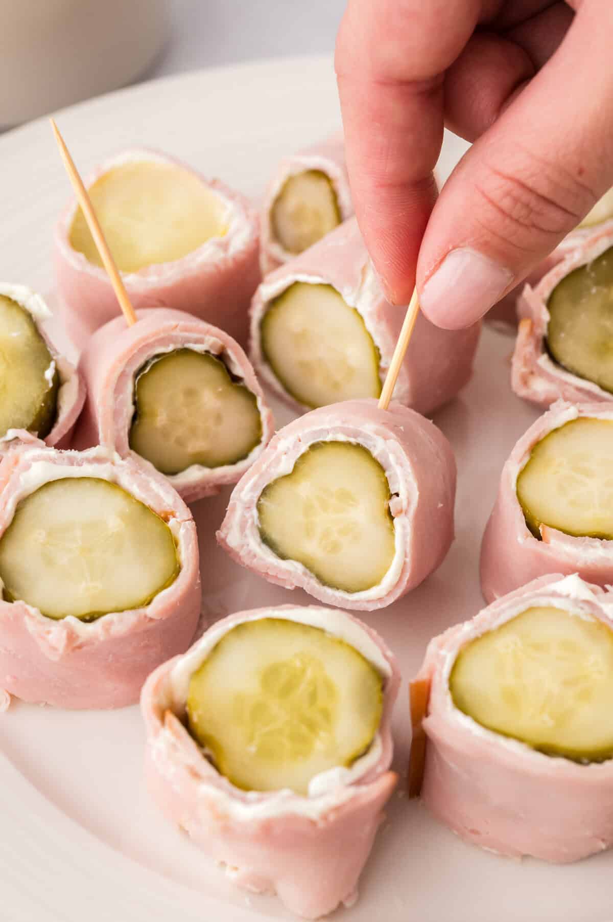 Hand grabbing a keto ham and pickle roll up.