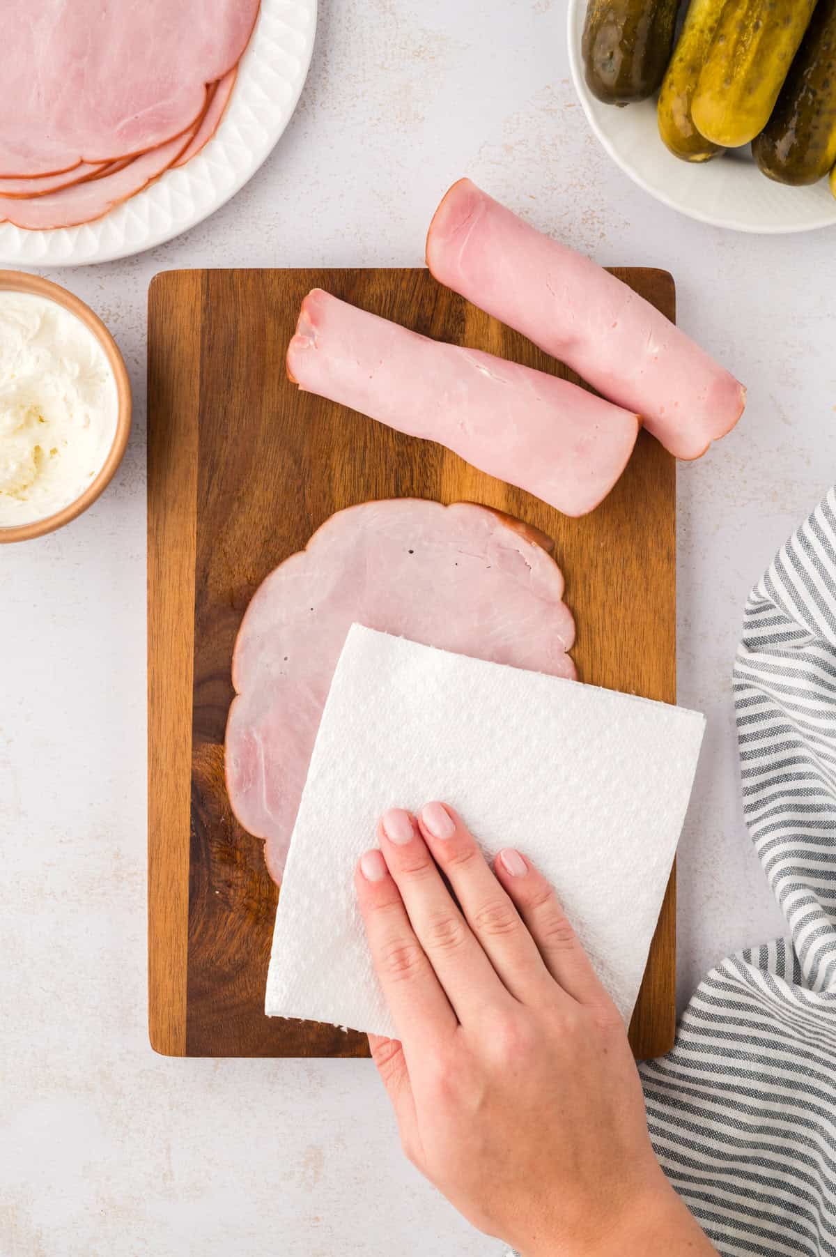 Deli ham being patted dry with a paper towel.