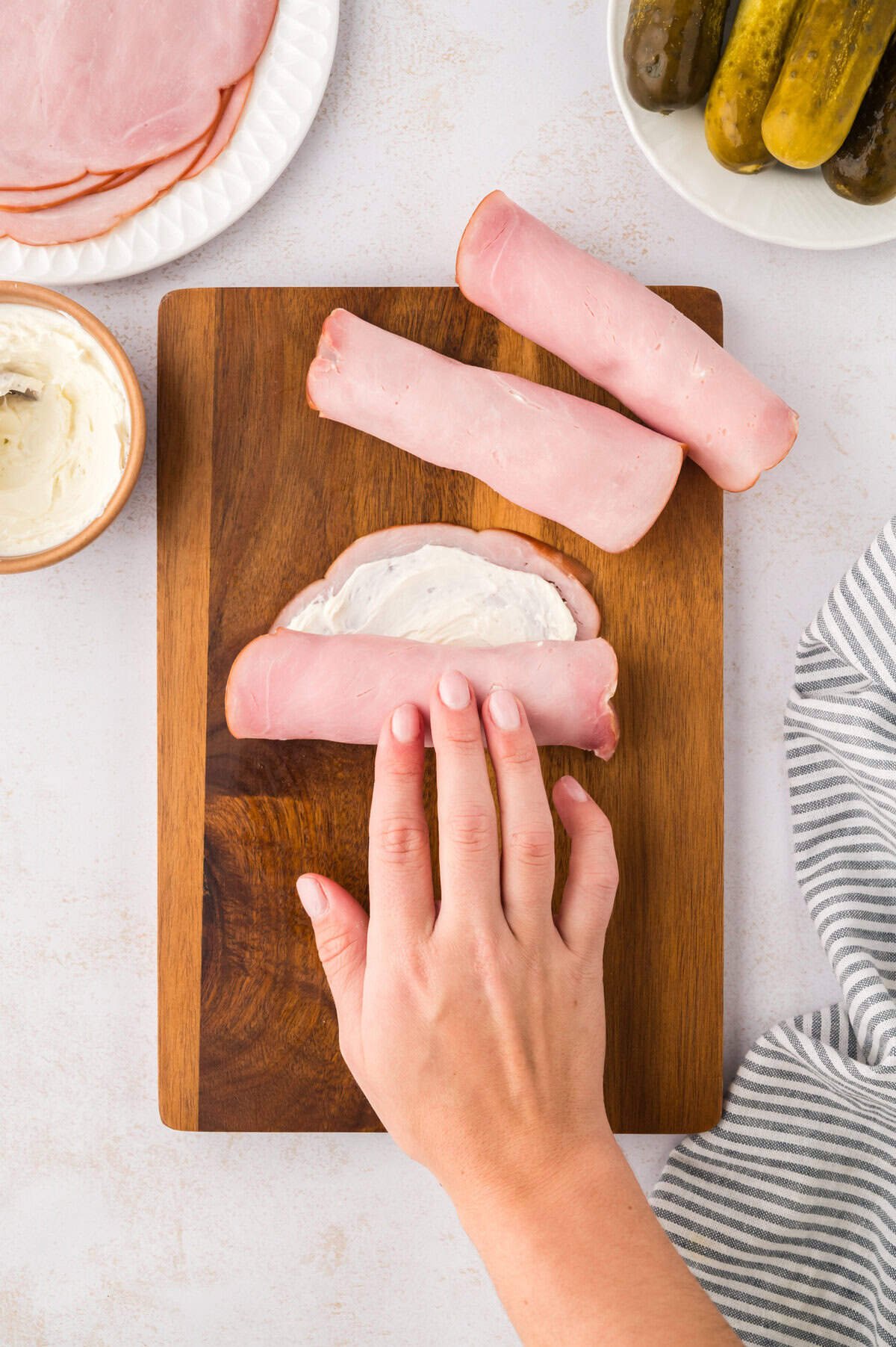 Pickle being rolled up in deli ham.