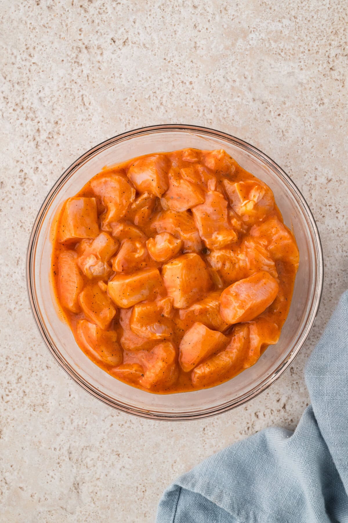 Chicken breasts chunks marinating in buffalo sauce.