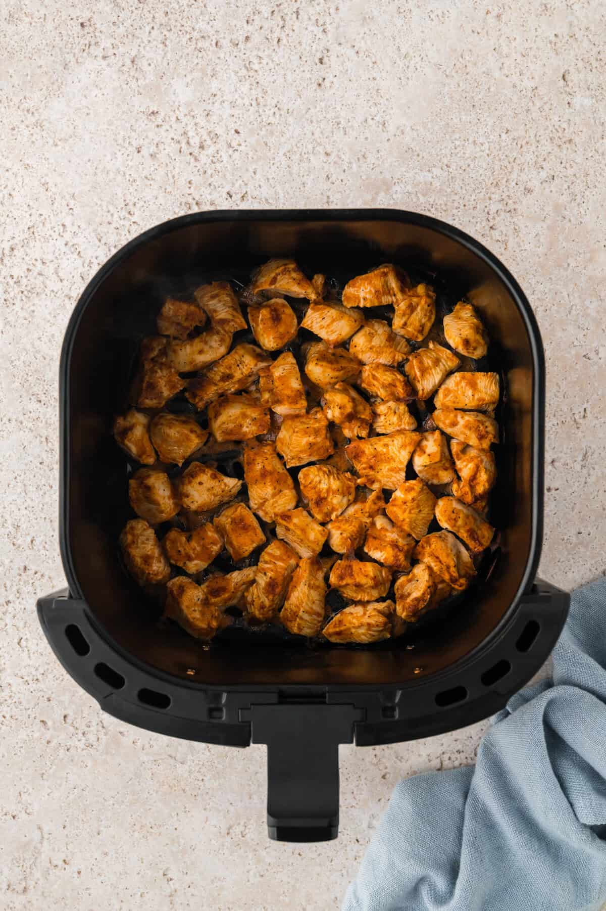 Air fried buffalo chicken bites in air fryer basket.