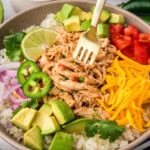 Bowl filled with crockpot salsa chicken, cauliflower rice, and cheese.
