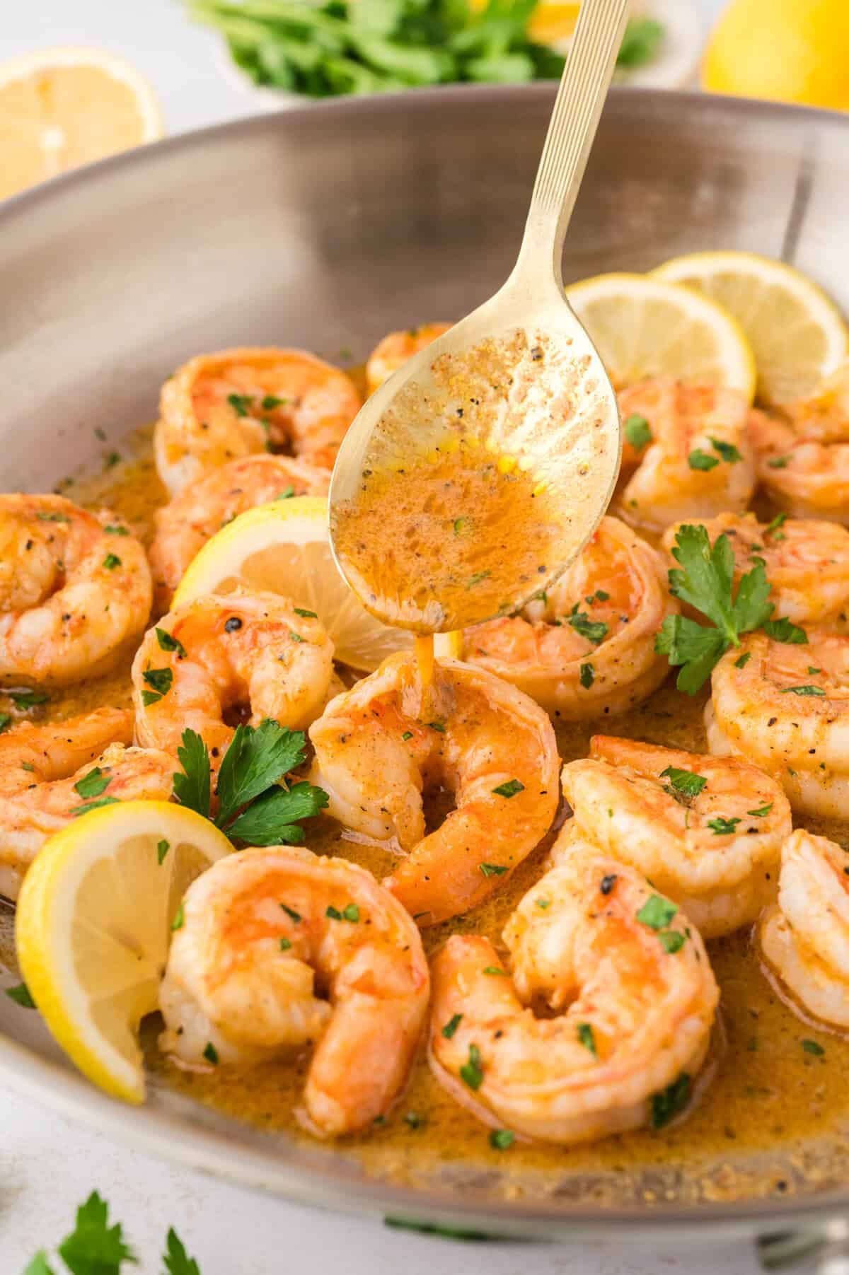 Lemon pepper shrimp being drizzled with sauce.