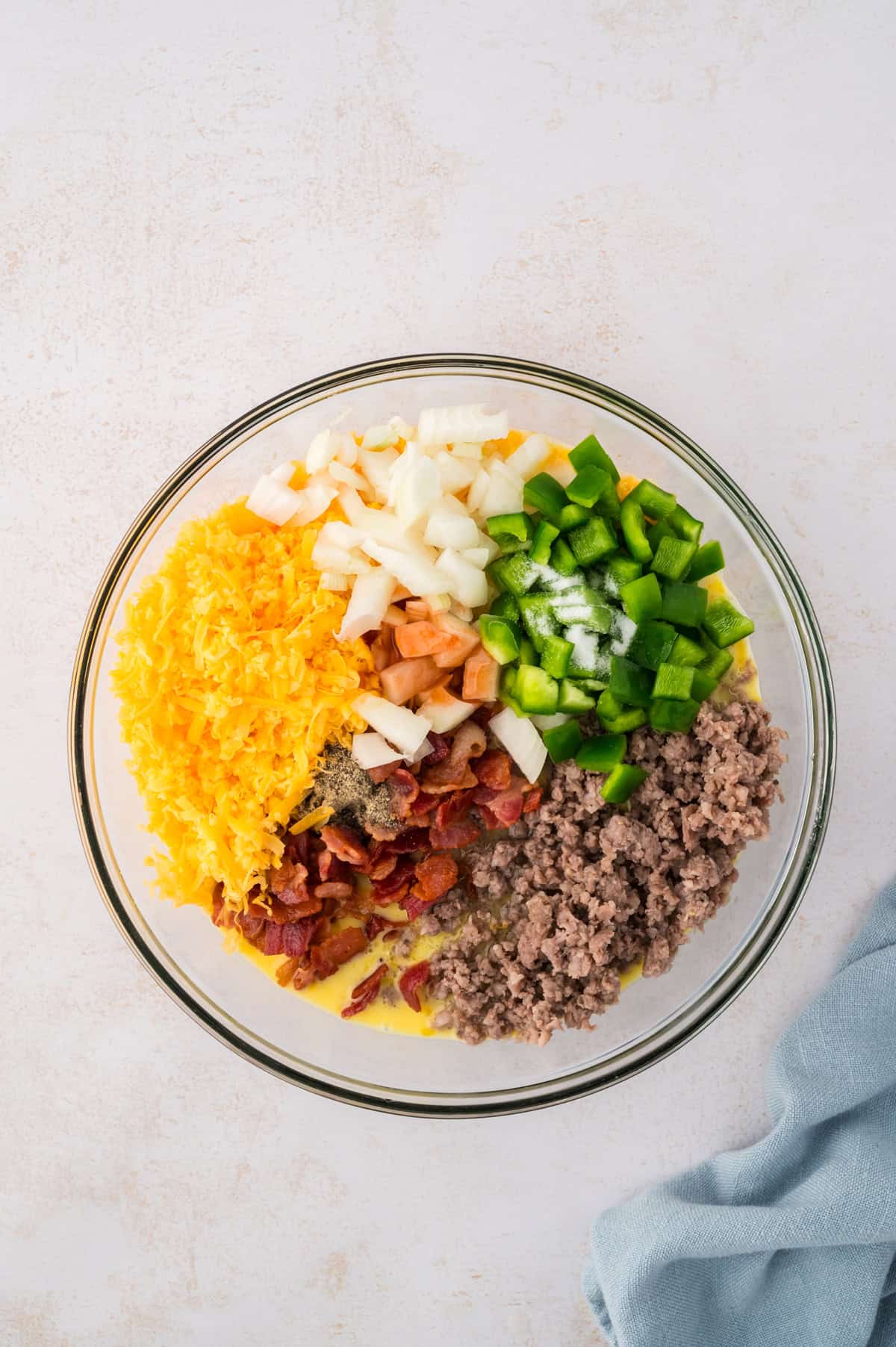 Sausage, bacon, and veggies in bowl with eggs.