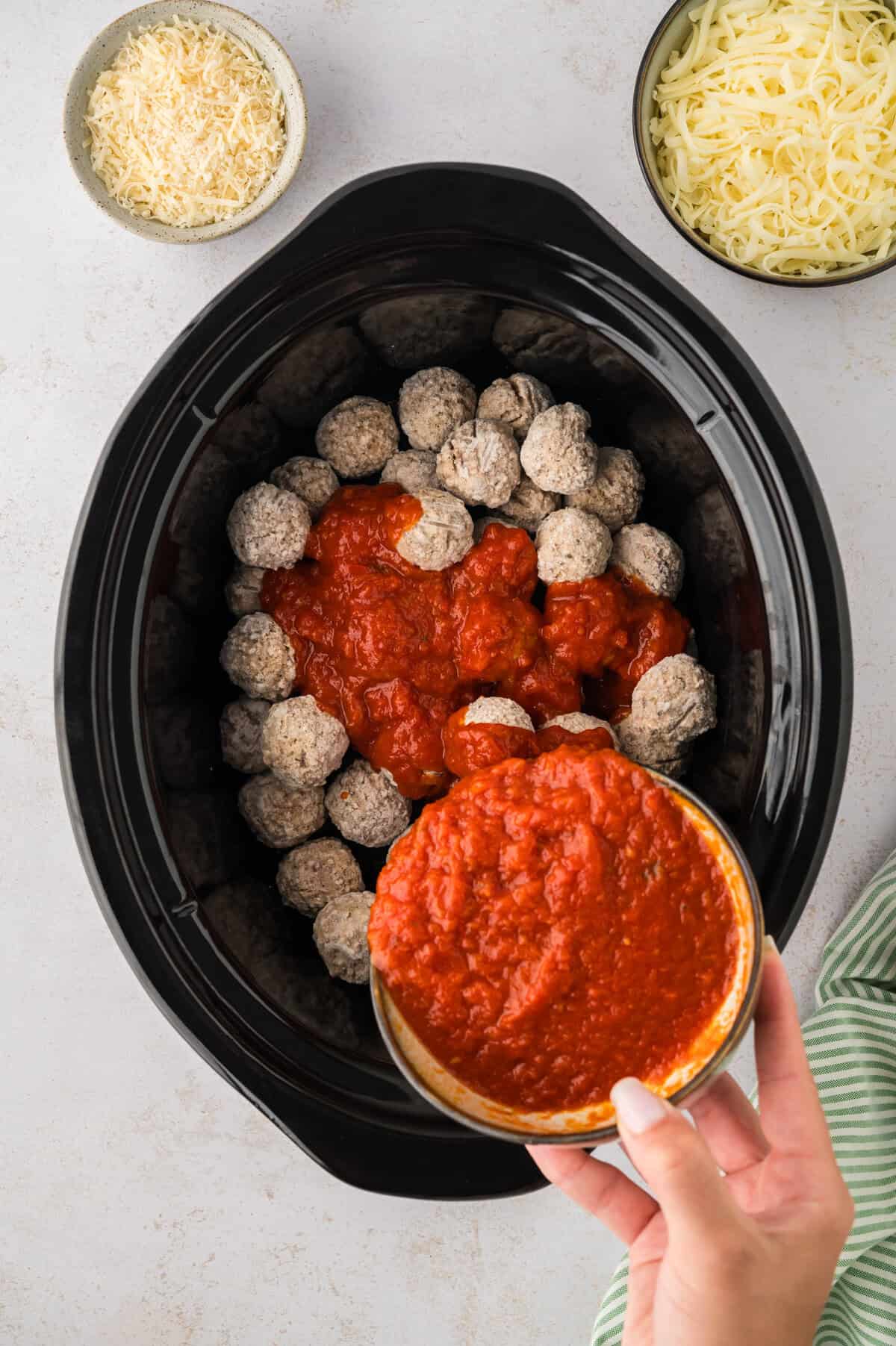 Frozen meatballs in slow cooker with tomato sauce.