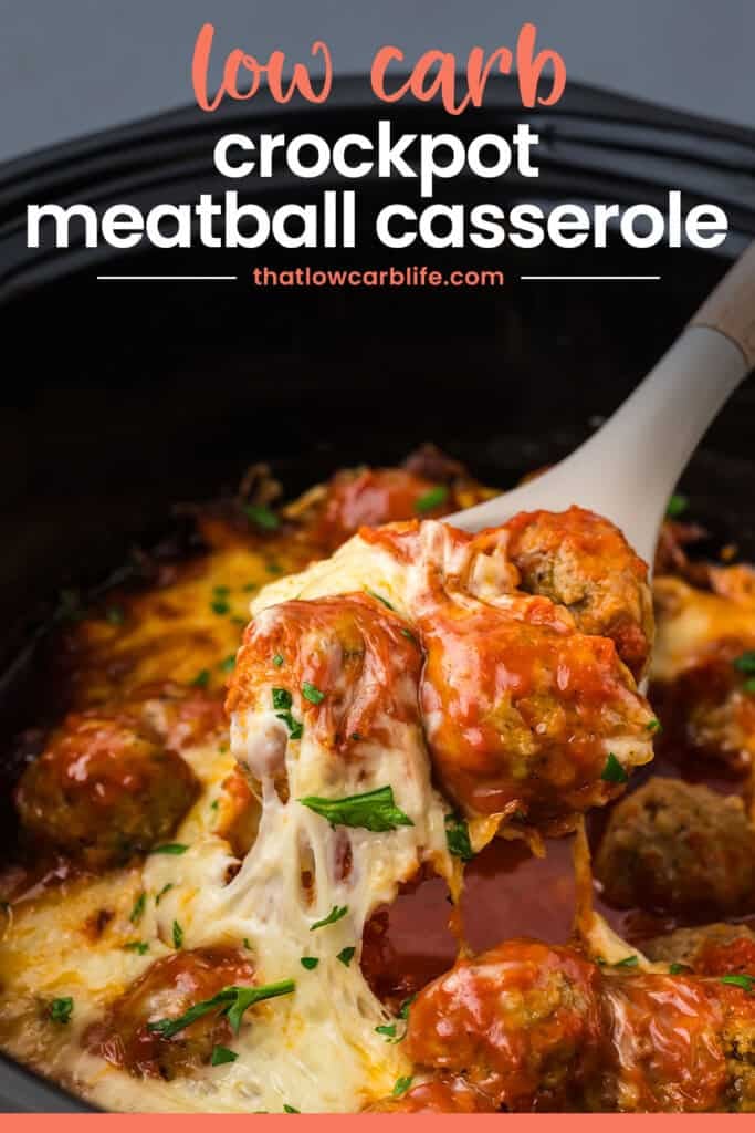 Spoon in crockpot covered with cheesy meatballs.